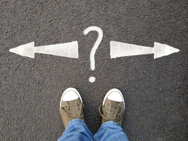 feet standing on asphalt with arrows pointing left and right with question mark